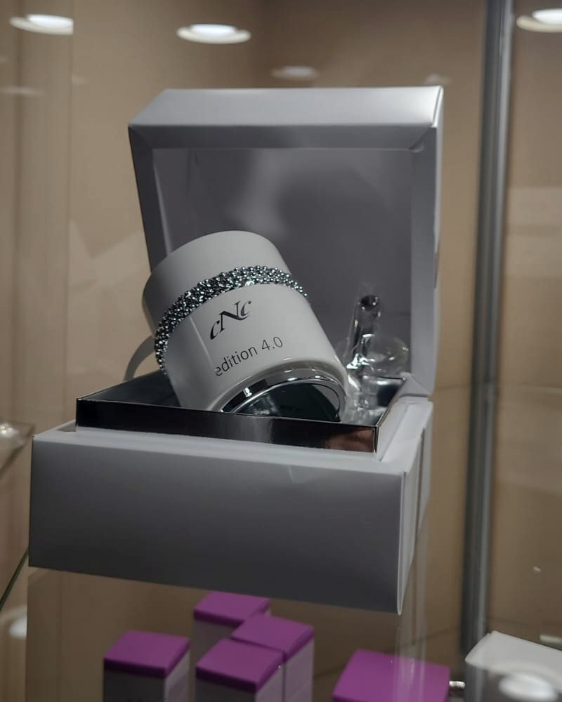 Beleuchtete Glasvitrine mit einem Cremetiegel in einer geöffneten Geschenkbox